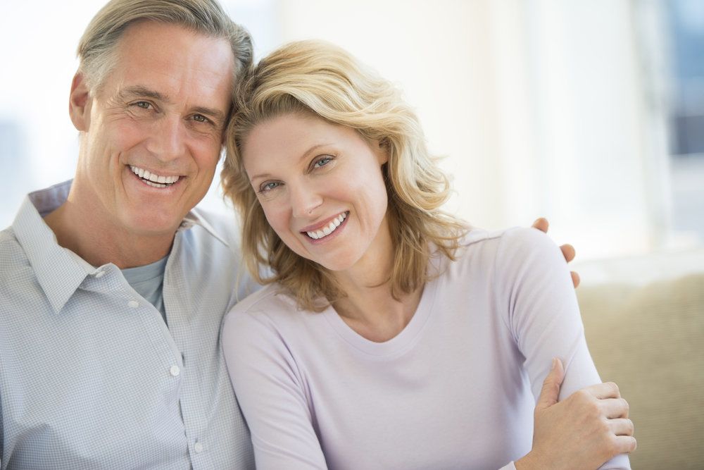 An attractive middle-aged couple smiling happily hold each other in a warm embrace.